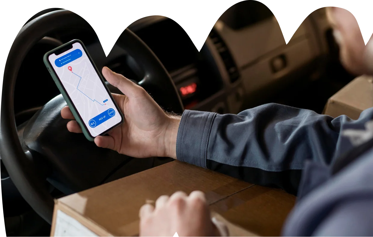 A person in a vehicle is holding a smartphone displaying a map app. A brown package lies on his lap, giving the impression of navigation and delivery.